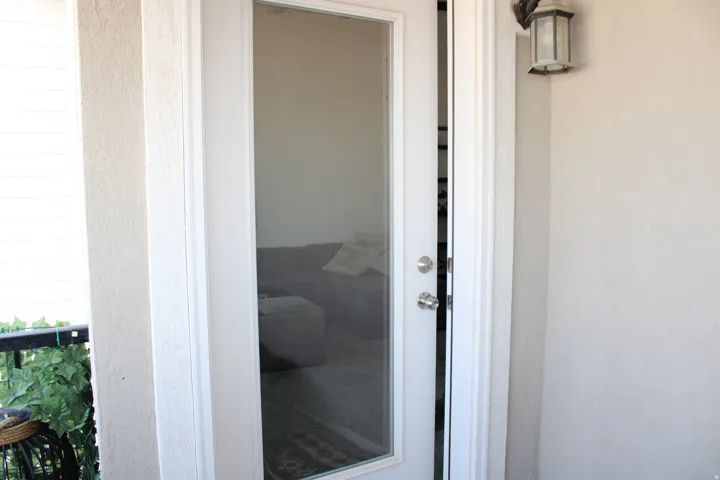 Exterior door with glass paneling and a wall-mounted light fixture