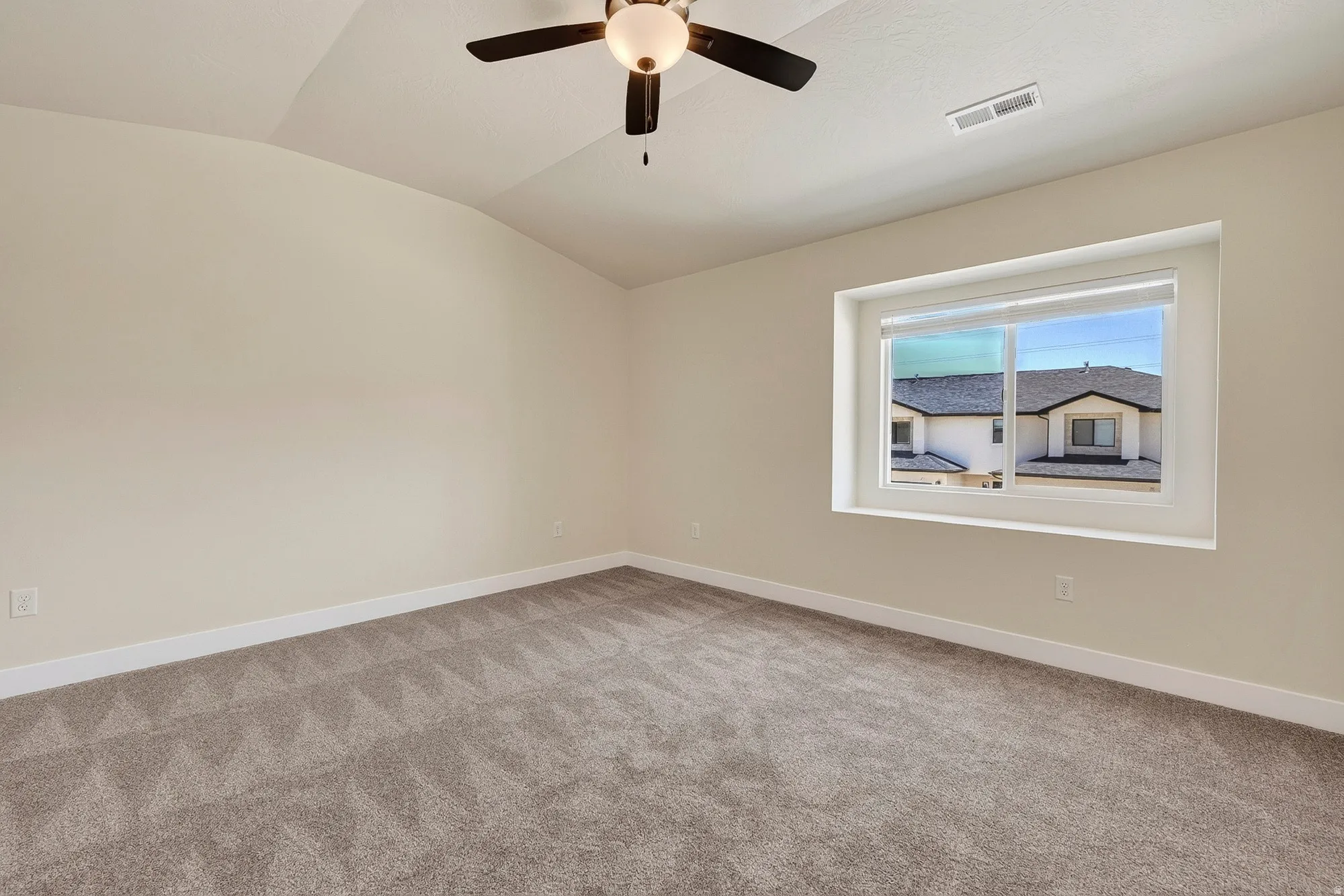 Spacious room featuring vaulted ceilings, neutral-toned walls, and plush carpeting