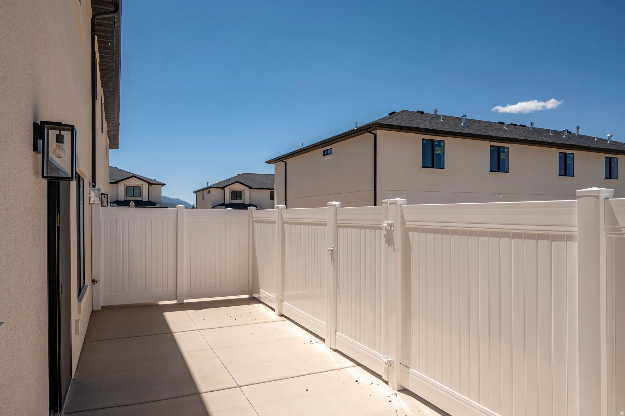 Private patio area featuring a concrete surface and a white vinyl privacy fence