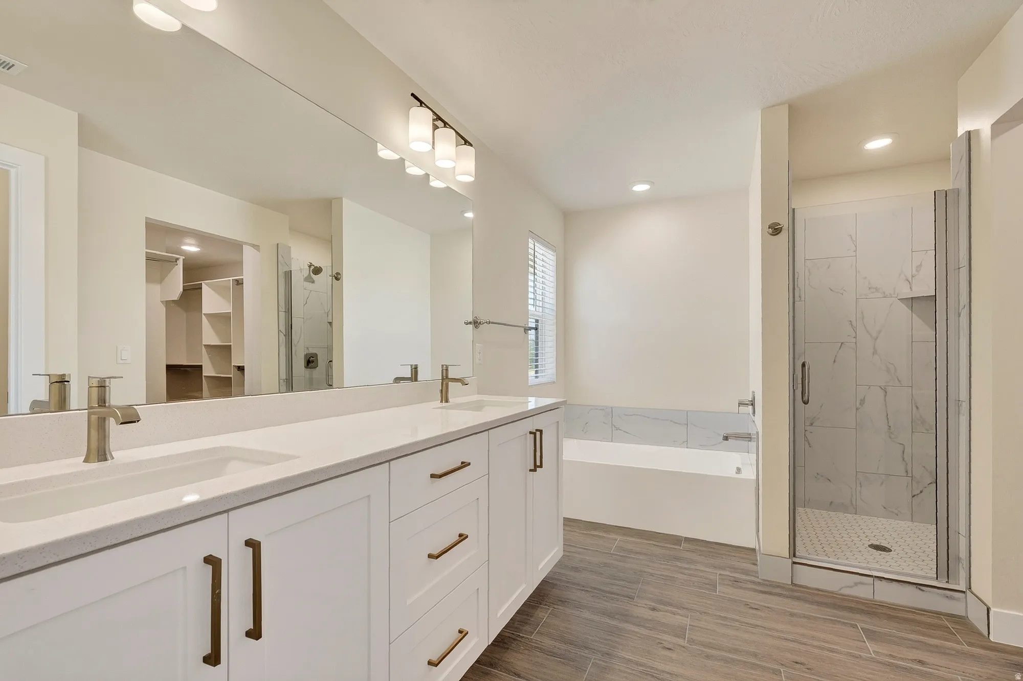 Dual vanity with white shaker-style cabinetry, bronze hardware, and undermount sinks