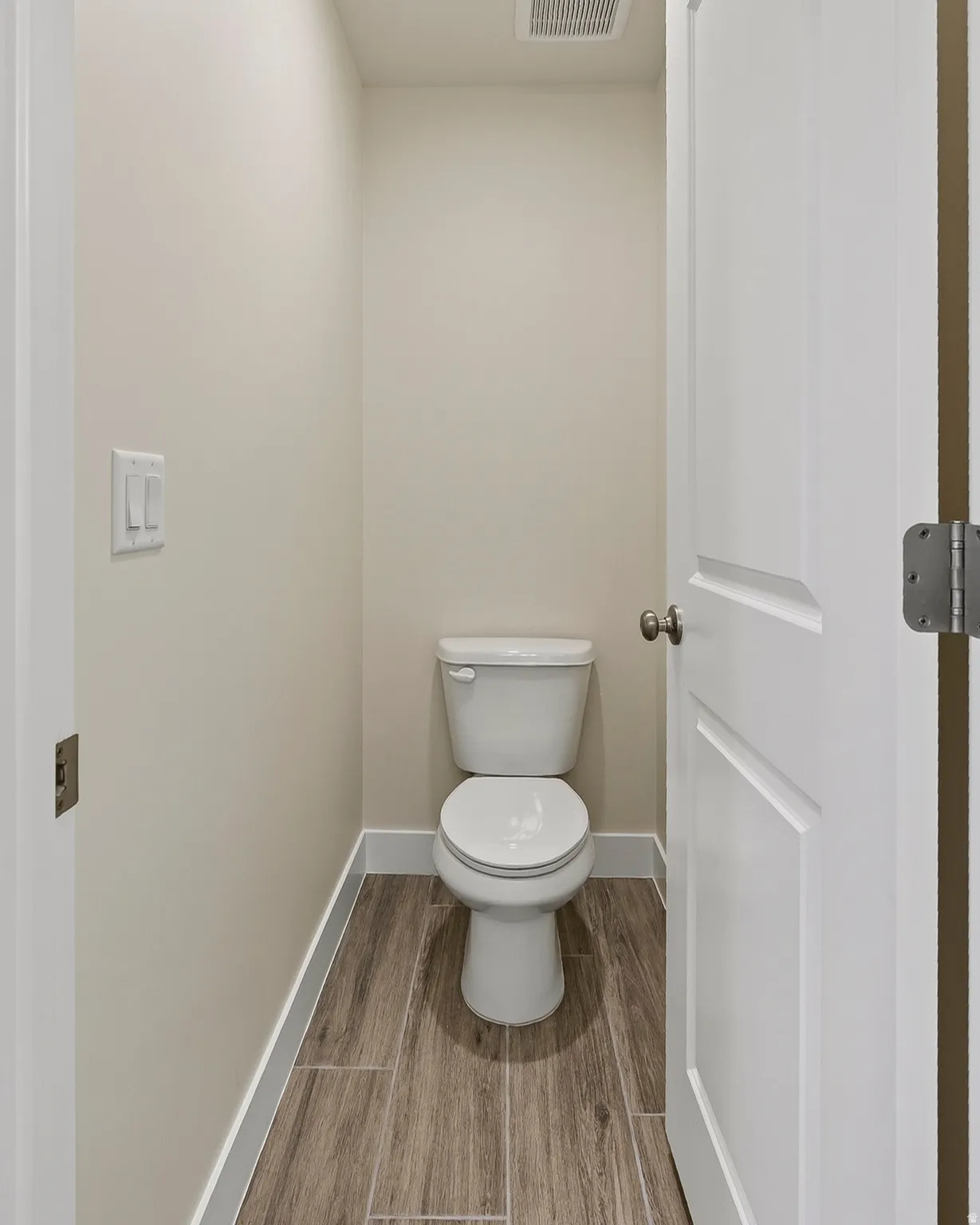 White two-piece toilet on wood-finish tile flooring