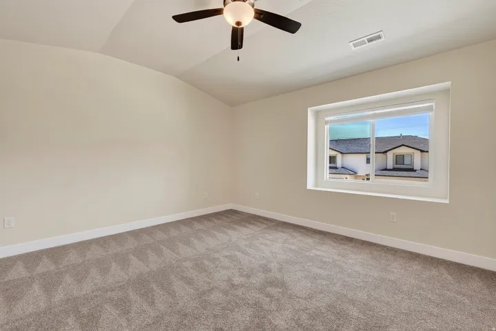 Spacious room featuring vaulted ceilings, neutral-toned walls, and plush carpeting