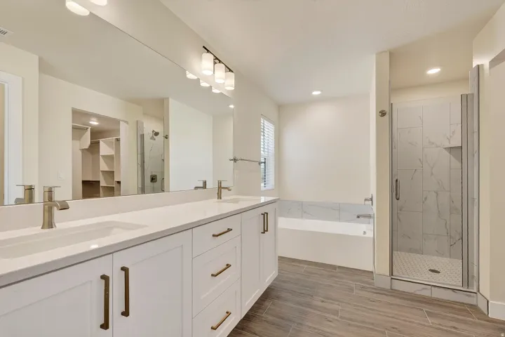 Dual vanity with white shaker-style cabinetry, bronze hardware, and undermount sinks