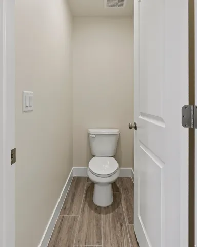 White two-piece toilet on wood-finish tile flooring