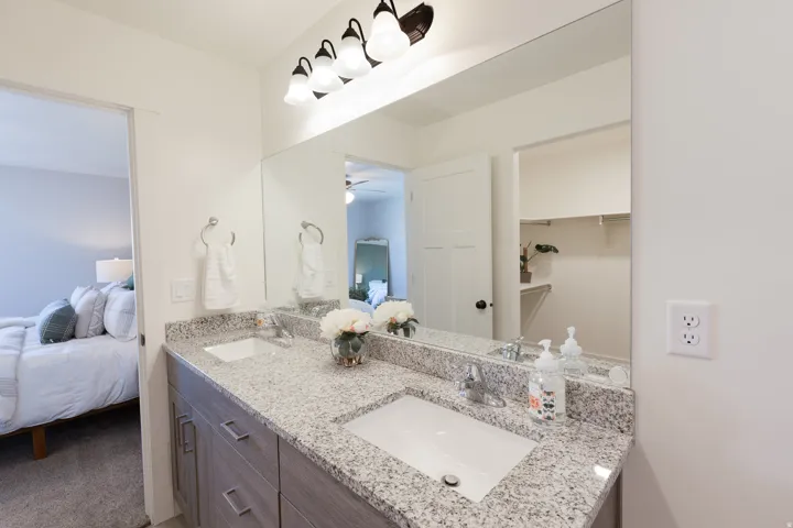 Dual vanity featuring undermount sinks, granite countertops, and wood-finish cabinetry