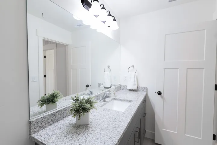 Double vanity with undermount sinks, granite-finish countertop, and a large wall-mounted mirror