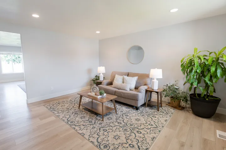 Recessed lighting illuminates the living space with light-toned walls and wood-finish flooring
