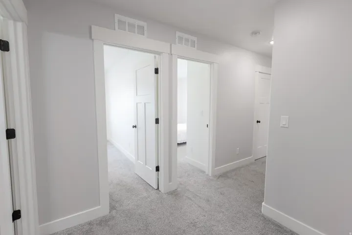 Light gray carpeting throughout, white trim, white walls, and white doors with black hardware