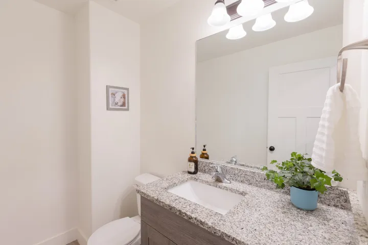 Bathroom featuring a vanity with a granite-style countertop, undermount sink, and wood-finish cabinetry