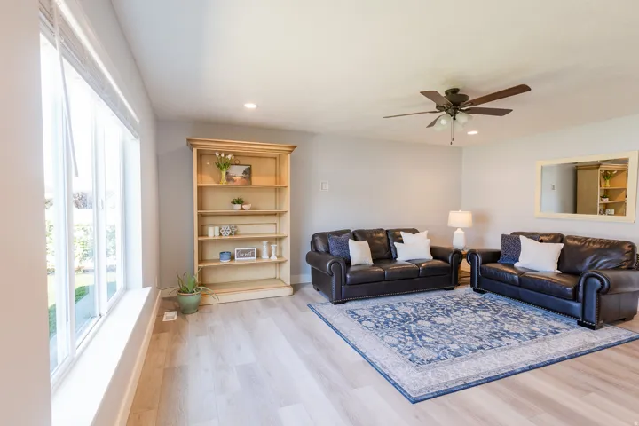 Light-toned wood-finish flooring, recessed lighting, ceiling fan, built-in shelving, and large windows