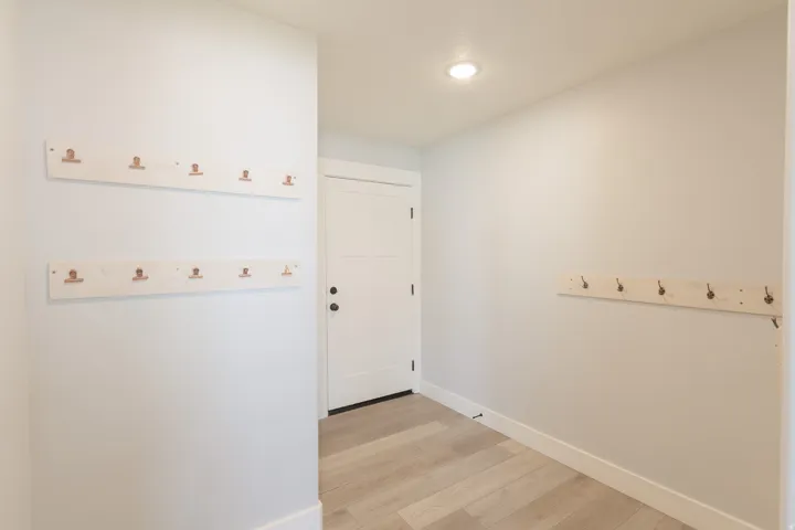Recessed lighting, light wood-finish flooring, white paneled door, and neutral wall tones