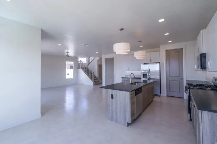 Modern kitchen featuring a central island with integrated sink, dark countertops, and stainless steel appliances