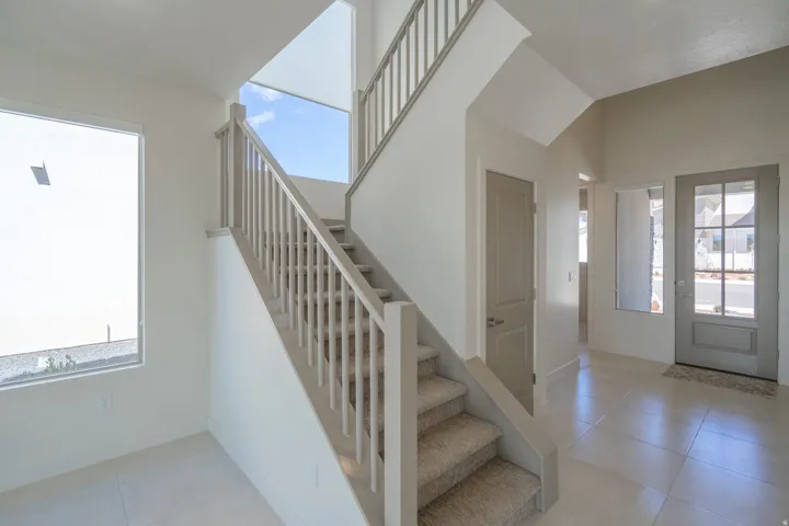 Staircase featuring carpeted treads, painted balusters, and a light-toned handrail
