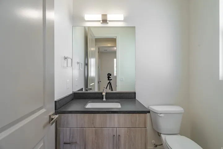 Modern bathroom featuring a wood-finish vanity with an integrated sink, dark countertop, and brushed nickel faucet