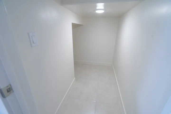 Bright, neutrally painted interior passage featuring tile flooring and overhead lighting