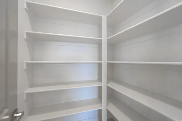 Expansive pantry featuring white shelving with a corner configuration, offering extensive storage capacity
