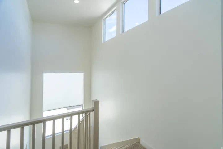 Stairwell featuring light-toned balusters, a frosted lower window, and a trio of upper transom windows