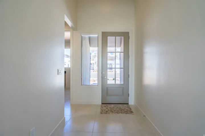 Entryway featuring a grey paneled door with multiple glass lites, a matching sidelite, and light-toned tile flooring