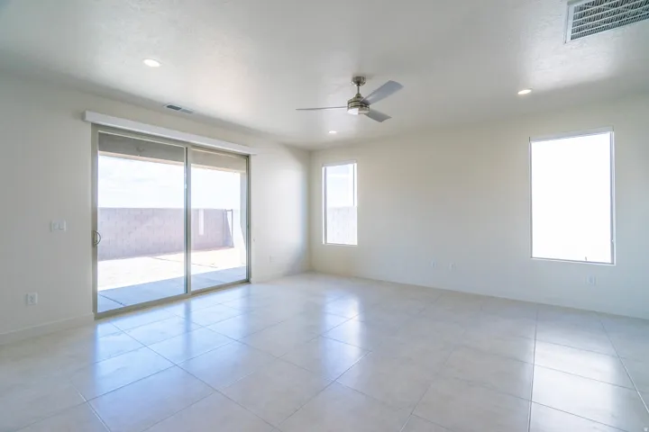 Expansive room featuring large format tile flooring, a brushed nickel ceiling fan, recessed lighting, multiple windows, and a sliding glass door to an outdoor space