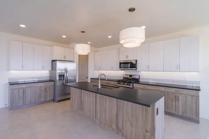 Modern kitchen featuring an expansive center island with an integrated sink and dark countertop