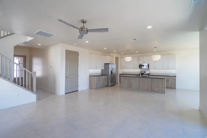 Open-concept living space featuring a modern kitchen with a large island, stainless steel appliances, and white cabinetry