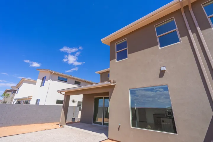 Rear exterior featuring a covered patio, expansive sliding glass door, and large picture windows