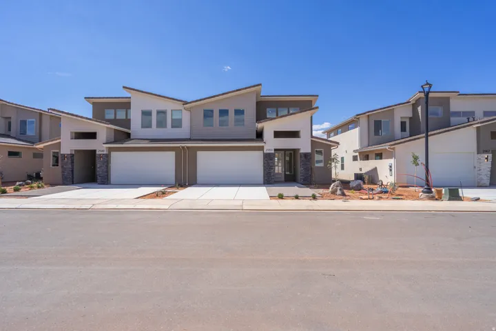 Modern multi-unit residence with a multi-level facade, stone pillar accents, and a two-car garage