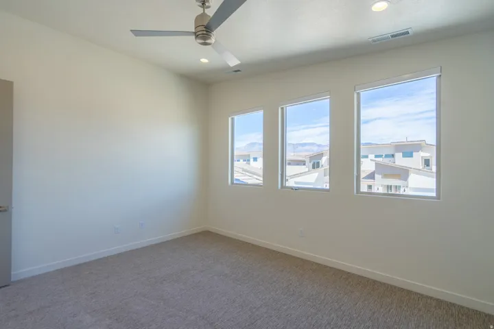 Room featuring three large windows, a modern ceiling fan with a brushed nickel finish, recessed lighting, and light-toned carpet flooring