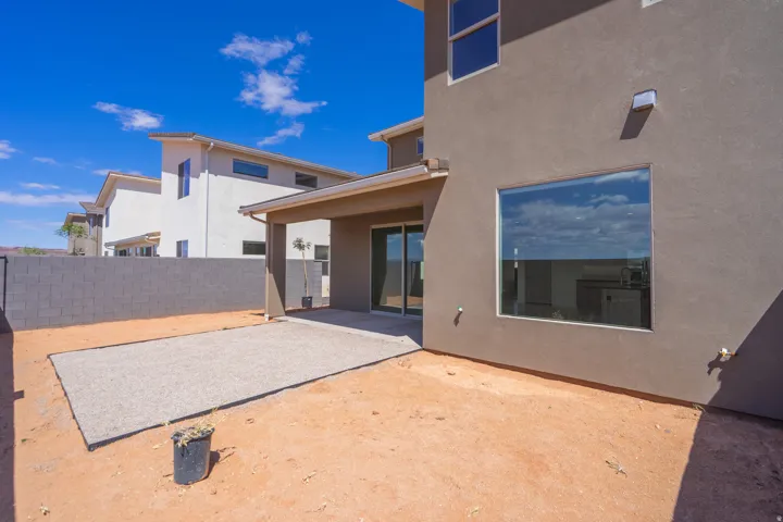 Exterior stucco siding featuring a large picture window and a covered patio with sliding glass doors