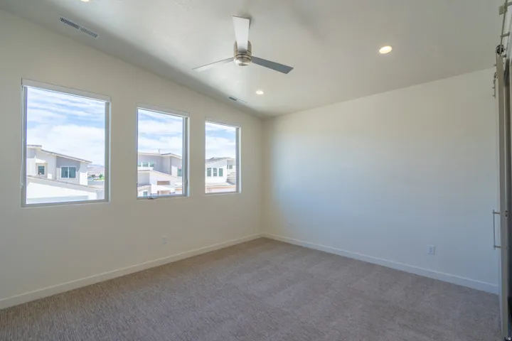 Spacious room featuring three rectangular windows, recessed ceiling lighting, a modern ceiling fan, and neutral-toned carpeting