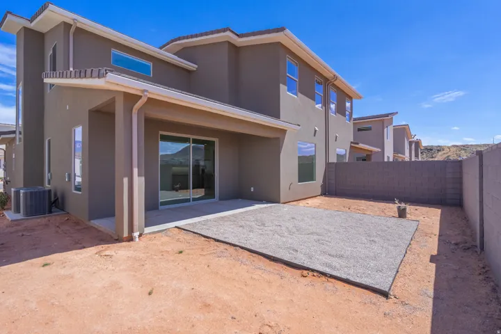 Rear exterior featuring a covered patio, sliding glass door entry, and an open gravel area