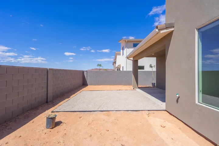 Expansive backyard featuring a covered patio, gravel area, and block wall fencing