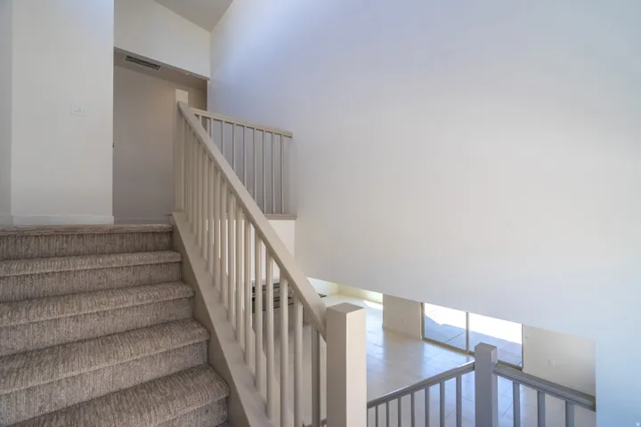 Carpeted staircase with light-toned balusters and railing