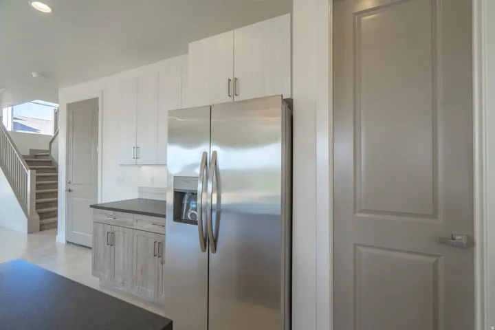 Modern kitchen featuring stainless steel appliances, light wood-finish cabinetry, dark countertops, and recessed lighting