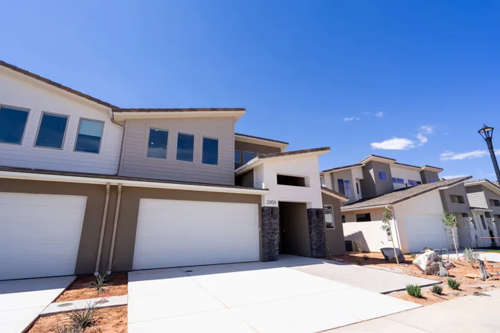 Contemporary townhome with a multi-textured facade, featuring clean lines, a two-car garage, and a covered entry
