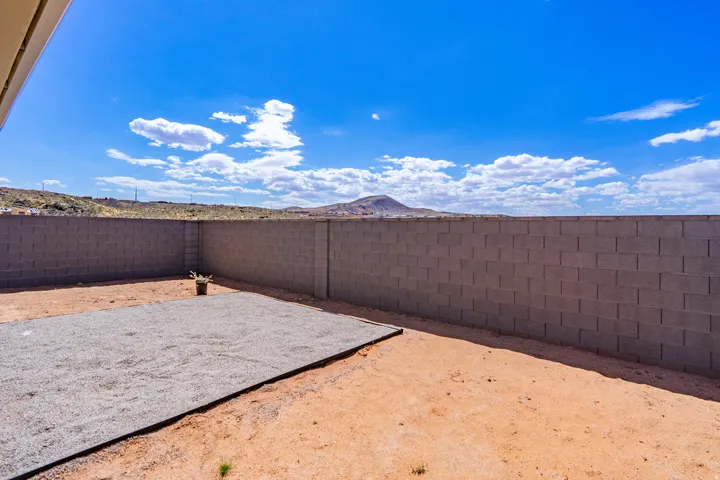 Spacious outdoor area featuring a full-height block wall perimeter, a large gravel-covered section, and a natural earth surface