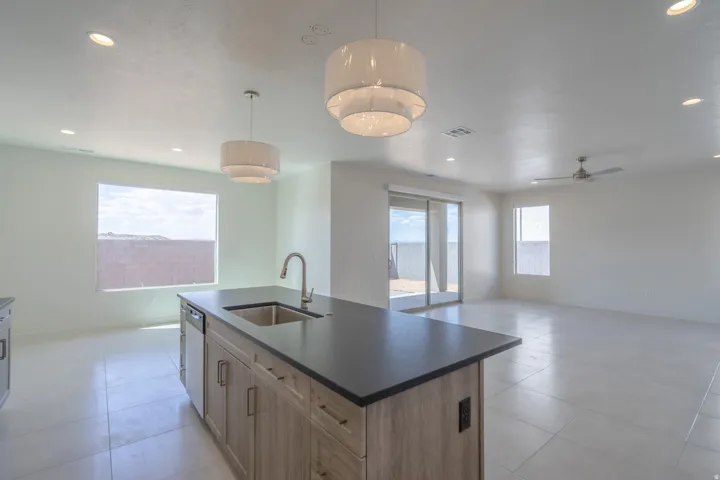 Kitchen island featuring a stainless steel sink, gooseneck faucet, integrated dishwasher, and wood-finish cabinetry with dark hardware