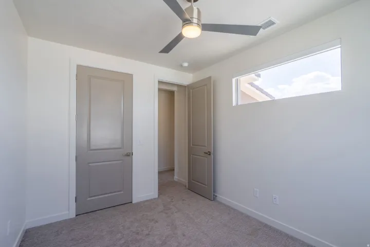 Neutral-toned carpeting complements the white walls and modern horizontal window