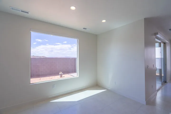 Spacious room featuring a large horizontal window, recessed ceiling lighting, light-toned walls, and tile flooring