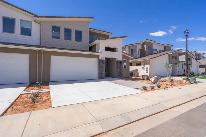 Contemporary townhome featuring a two-car garage, concrete driveway, and stone facade accents
