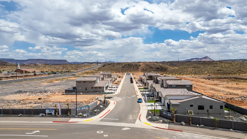 Modern residential development featuring a paved road, established landscaping, and desert mountain scenery