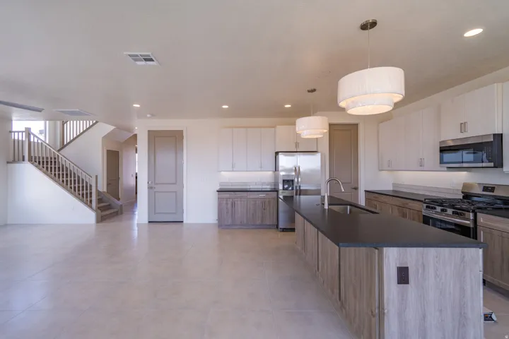 Open-concept kitchen featuring an expansive island with a sink, stainless steel appliances, and a gas range