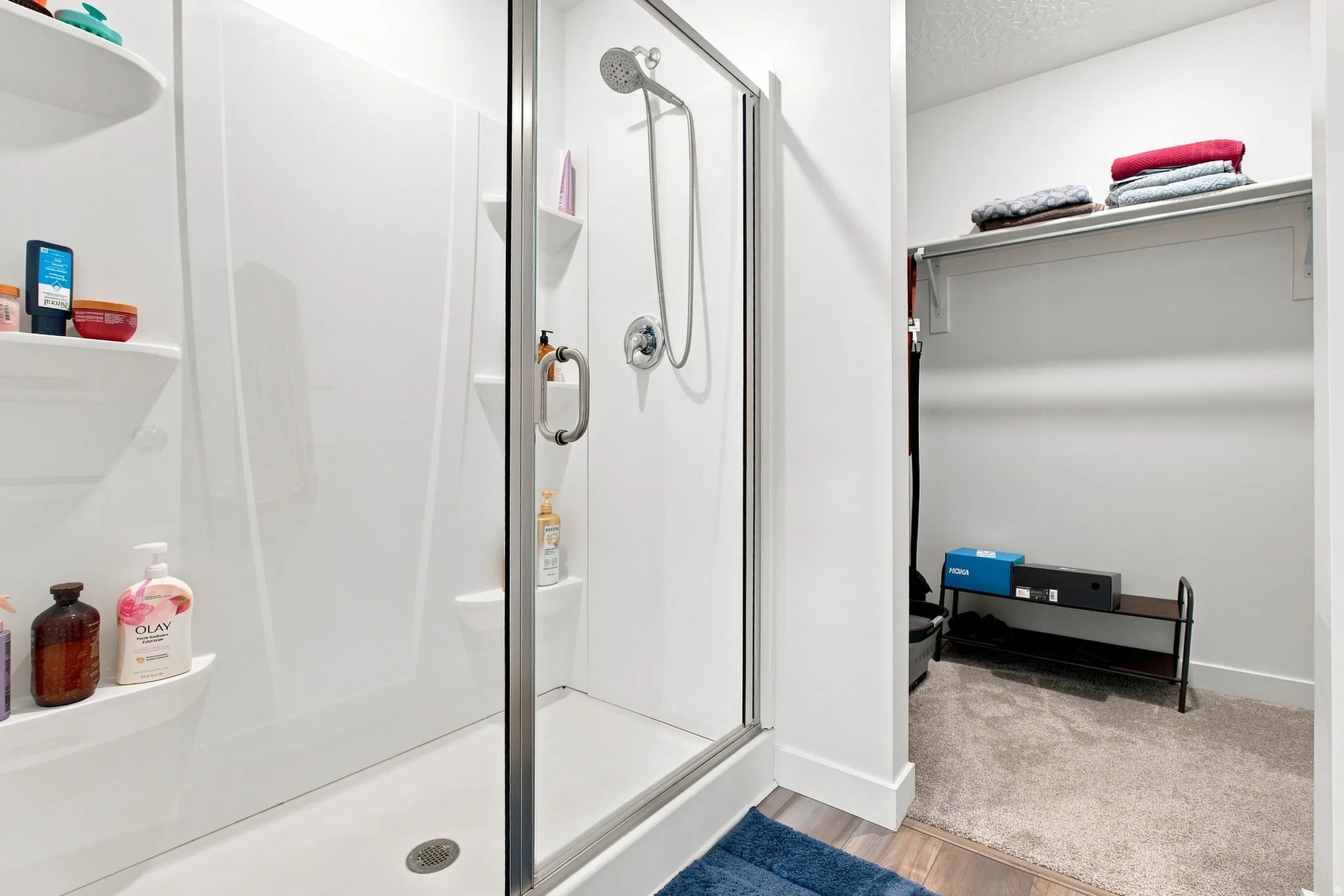 Shower with clear glass enclosure, overhead shower fixture, and integrated shelving