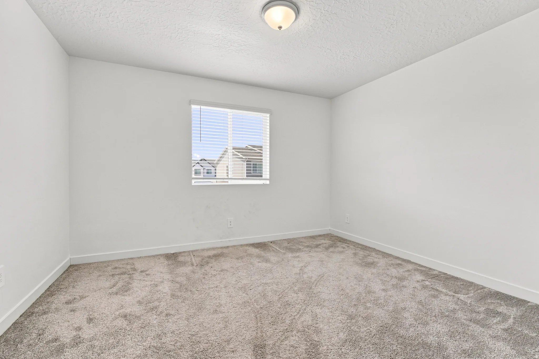 Wall-to-wall carpeting, neutral wall finishes, recessed window with blinds, and ceiling-mounted light fixture