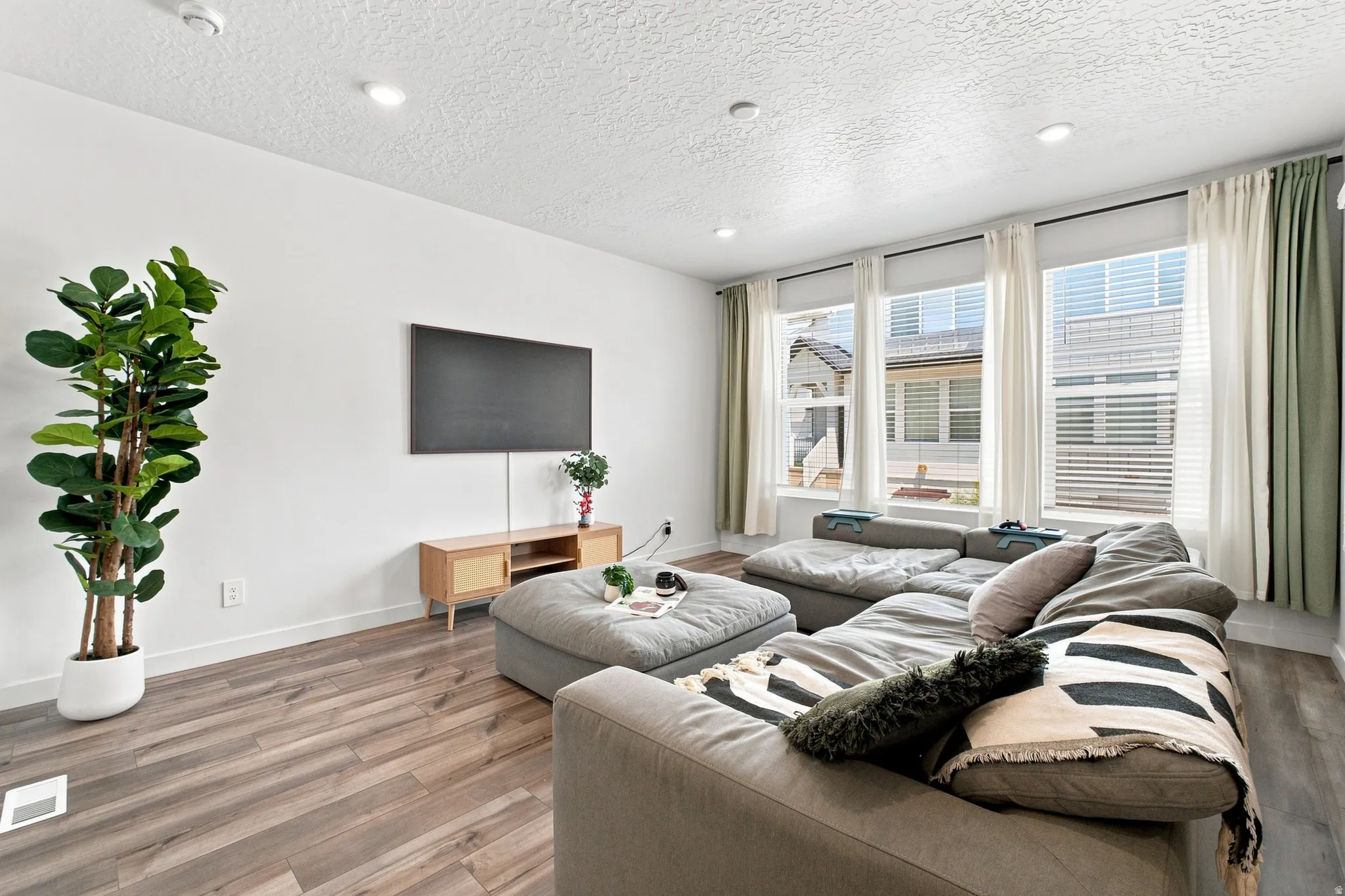Recessed lighting, wood-finish flooring, multiple large windows, and a built-in entertainment console