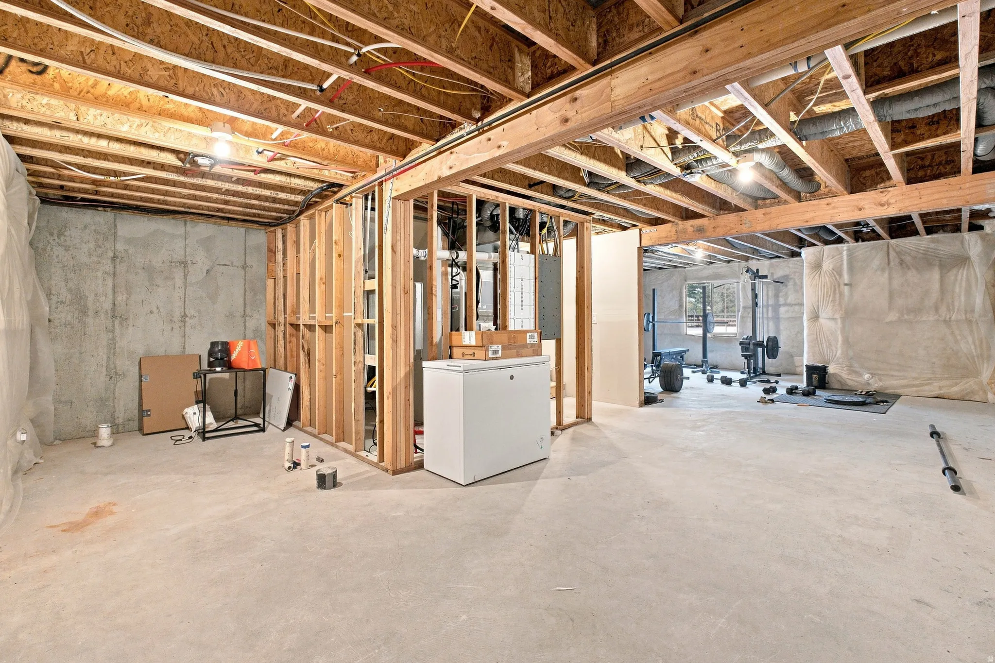 Unfinished basement with exposed wooden joists and framing, concrete walls, and a concrete floor