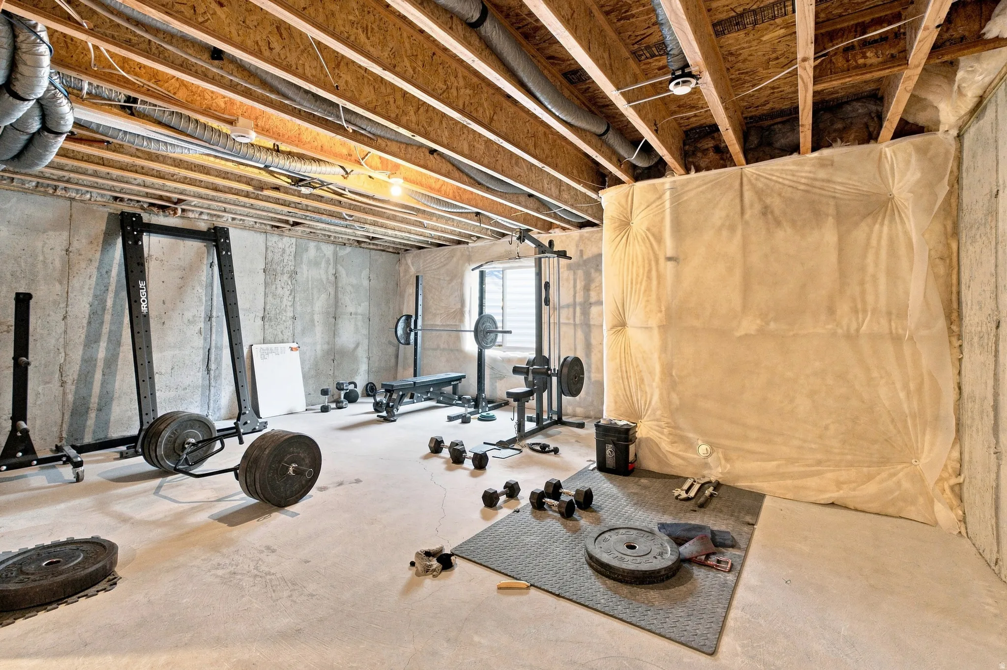 Unfinished concrete basement with exposed wood joists and concrete walls