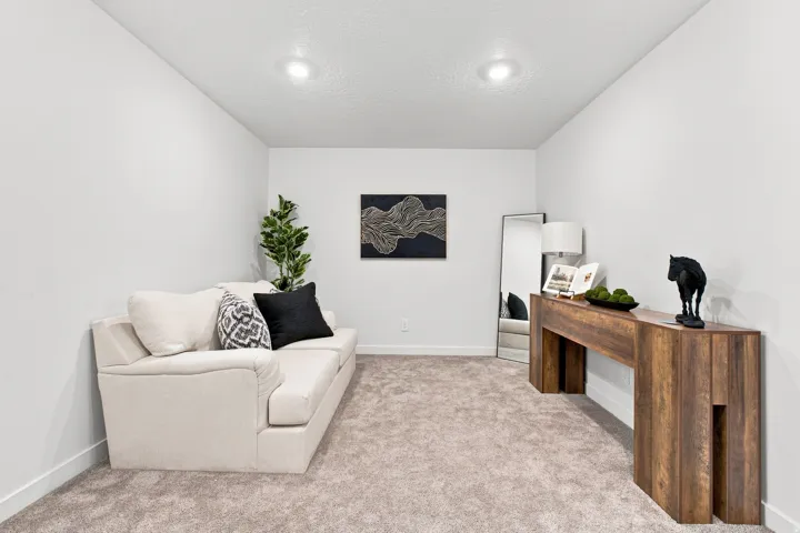 Recessed ceiling lighting, textured ceiling, neutral wall paint, carpet flooring, wood-finish console table