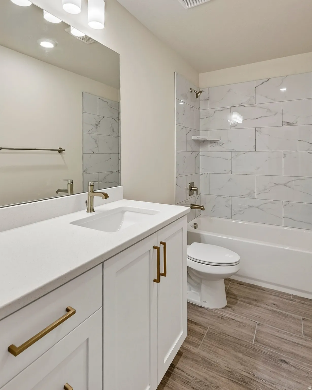 White vanity with brass hardware, undermount sink, and light-colored countertop