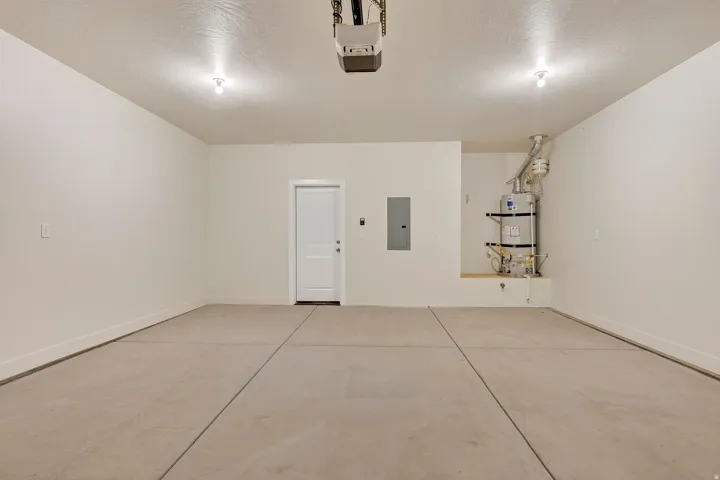 Spacious garage with concrete flooring, recessed lighting, and a prominent water heater installation